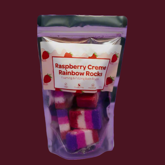A pouch of mini bright coloured bath bombs with a plain raspberry coloured background