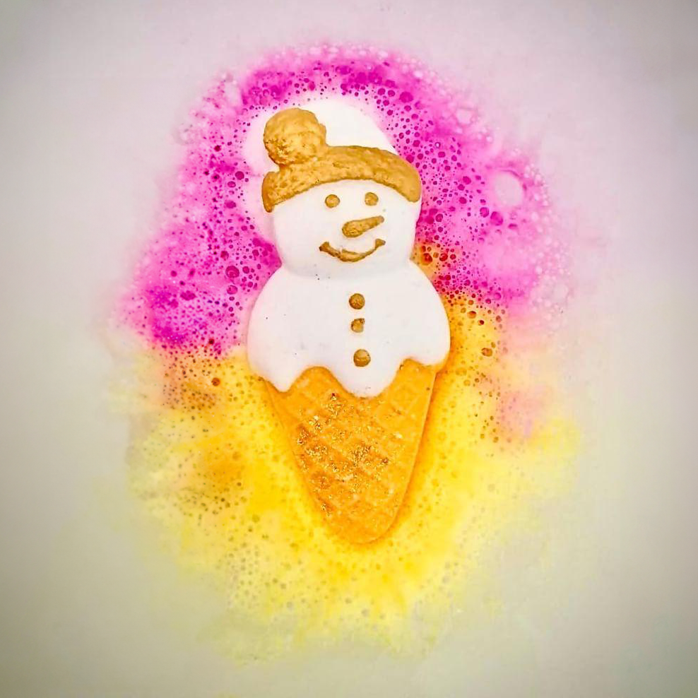 Vegan ice-cream snowman bath bomb which is putting heaps of pink and yellow colour into bath water