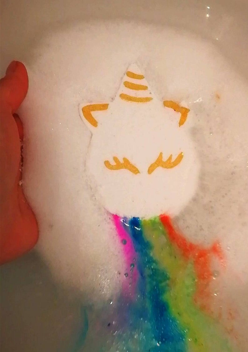 Unicorn shaped vegan bath bomb fizzing a rainbow of colours into the bath